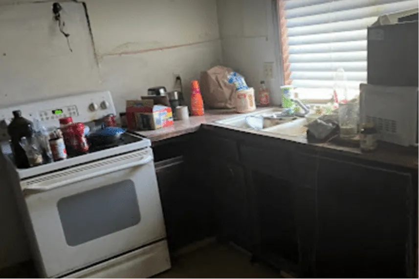 Cluttered kitchen with a stove, sink, and various items on the countertop, illustrating a home in need of repairs for quick cash sale by Portland Cash Buyers.
