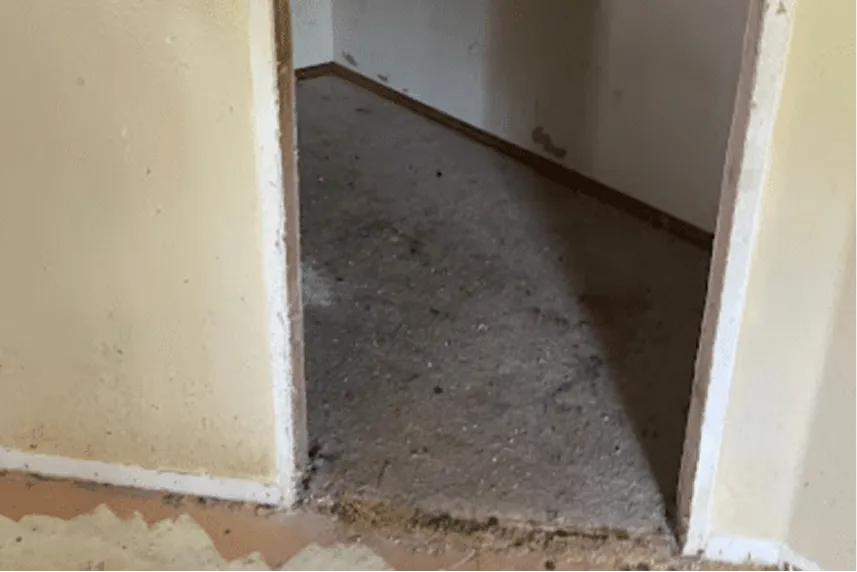 Interior view of a room showing a doorway with dirty walls and flooring, representing a house in need of repairs, relevant to Portland Cash Buyers' services for buying homes as-is.
