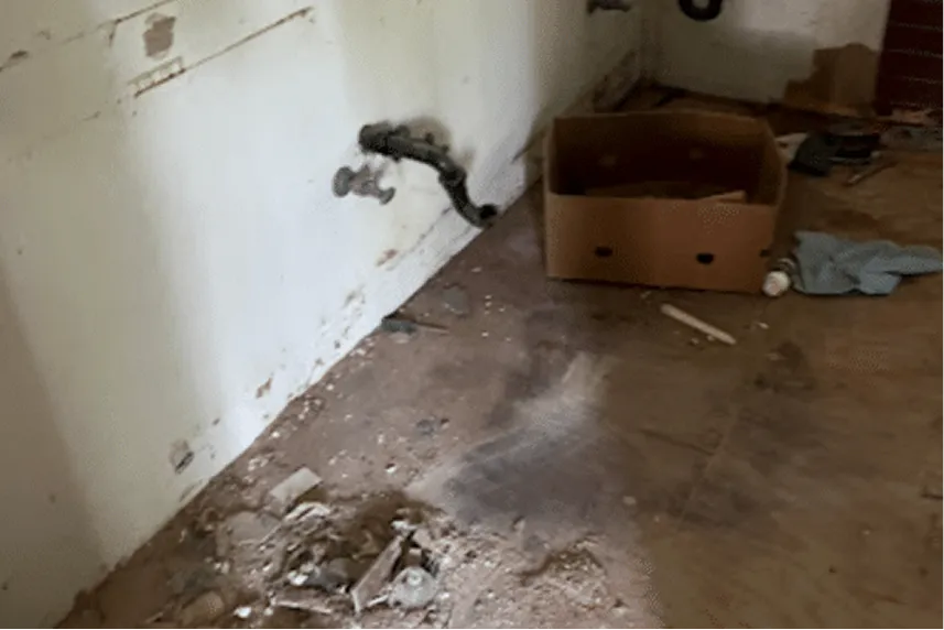Interior of a distressed home showing debris, exposed plumbing, and a cardboard box, representing properties needing repairs for quick cash sales by Portland Cash Buyers.