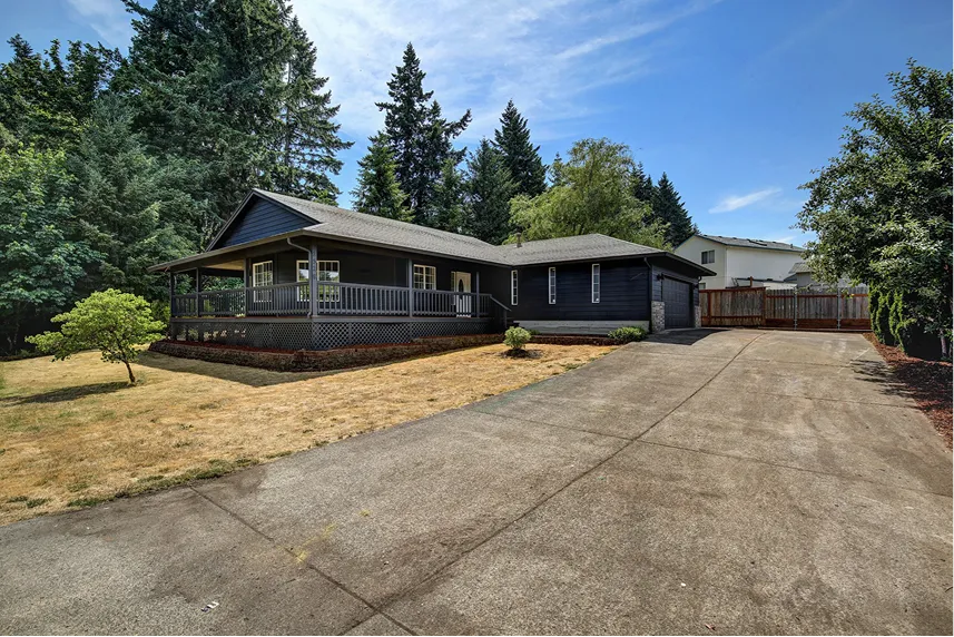 Single-story black house with a front porch, surrounded by trees and a gravel driveway, representing Portland Cash Buyers' commitment to buying homes as-is for cash.