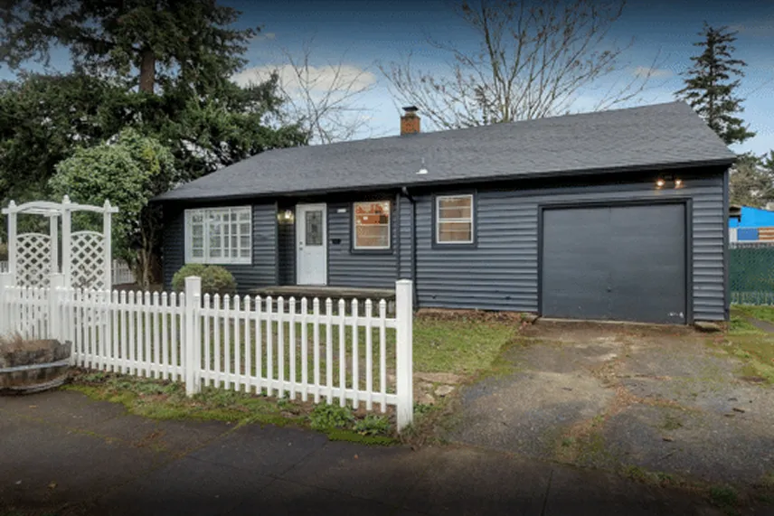 Blue house with white picket fence and garage, representing Portland Cash Buyers' commitment to buying homes as-is for cash offers.