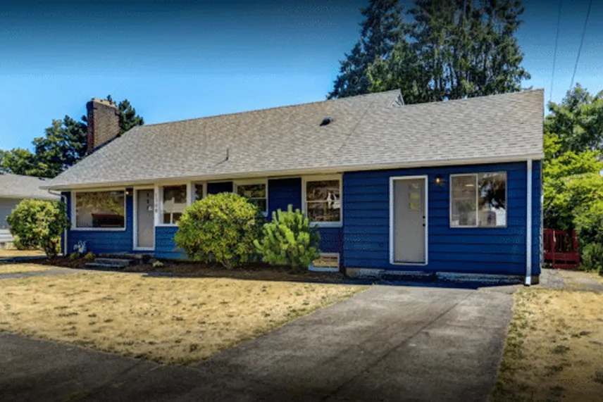 Blue single-story house with a well-maintained front yard, showcasing a cash offer opportunity from Portland Cash Buyers for homeowners looking to sell as-is.